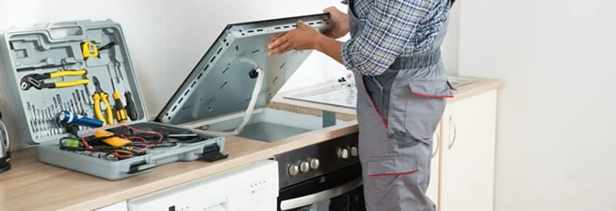 Cooktop repair technician lifting a built-in stovetop for service in Bradenton, FL