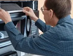 Appliance repair technician replacing a microwave vent filter in Bradenton, FL