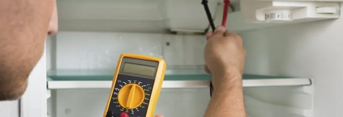 Refrigerator repair technician testing electrical components with a multimeter in Bradenton, FL