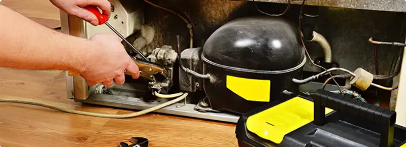 Refrigerator repair technician fixing the compressor and wiring in Bradenton, FL